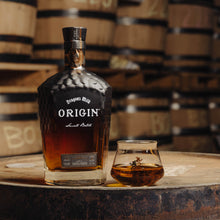 Load image into Gallery viewer, Bottle of Dragon's Milk Origin whiskey on a barrel with a glass filled with whiskey.