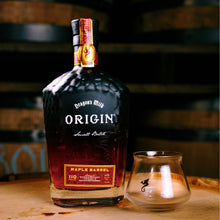 Load image into Gallery viewer, Bottle of Dragon's Milk Origin Maple Barrel whiskey with a glass on a wooden surface with barrels in the background