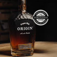 Load image into Gallery viewer, Bottle of Dragon's Milk Origin whiskey with an award badge on a wooden surface.