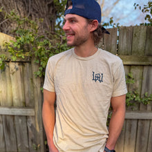 Load image into Gallery viewer, A man wearing a Walleye Run Whiskey T-Shirt standing against a fence.