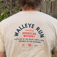 Load image into Gallery viewer, Person wearing a 'Walleye Run American Whiskey' t-shirt outdoors.
