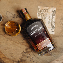 Load image into Gallery viewer, Bottle of New Holland Whiskey Origin on a wooden barrel with a glass.
