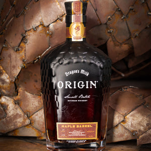 Bottle of Dragon's Milk Origin Maple Barrel bourbon whiskey with a rustic background