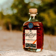 Load image into Gallery viewer, Bottle of Walleye Run bourbon whiskey on a wooden surface with a blurred natural background
